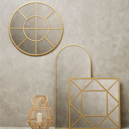 Three gold geometric mirrors on a beige wall with a woven basket and candle.
