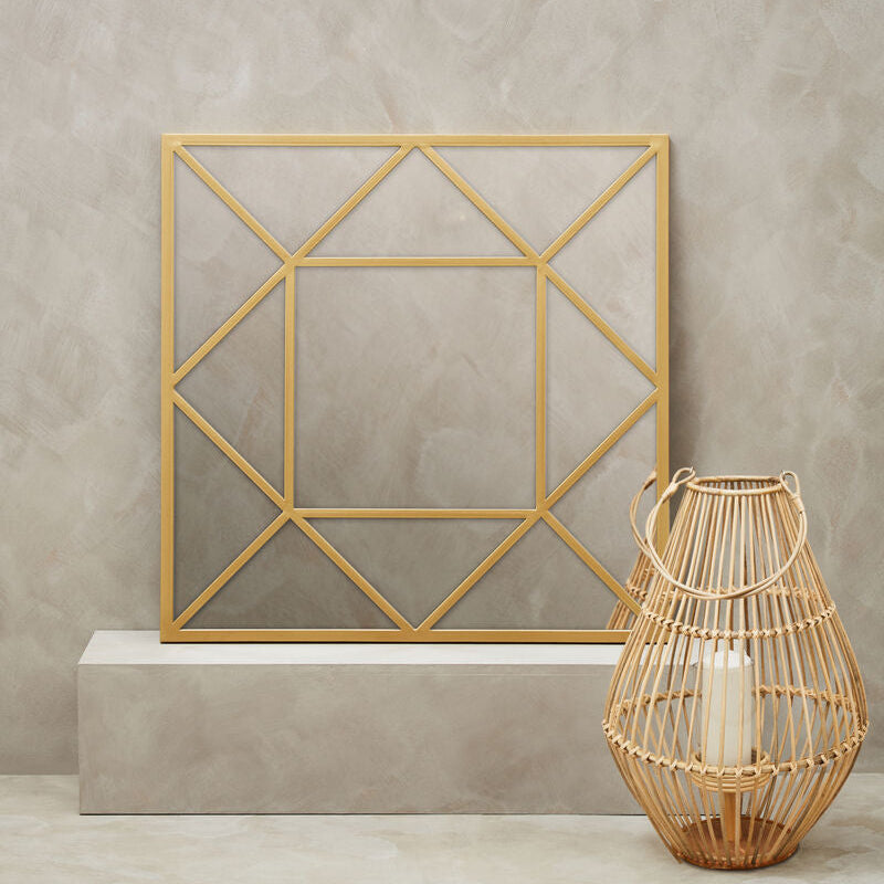Gold geometric mirror and wicker lantern on a neutral background