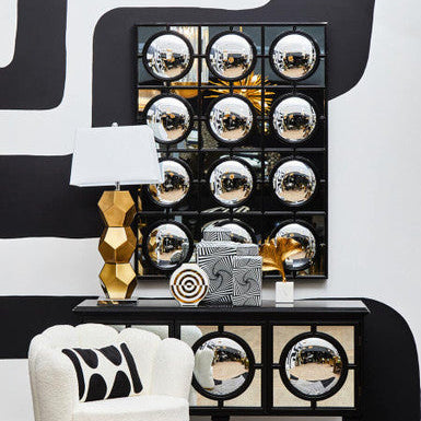 Decorative console table with mirror finish, white chair, and abstract wall art.