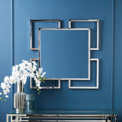 Decorative console table with mirror and flowers against a blue wall