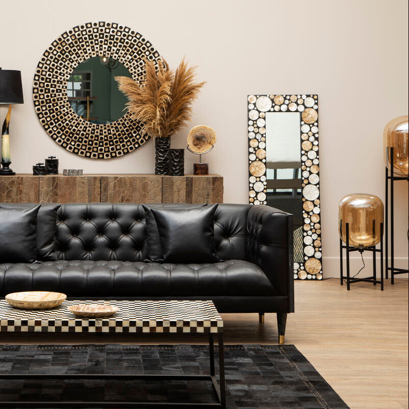 Modern living room with black leather sofa, wooden coffee table, and decorative mirrors.