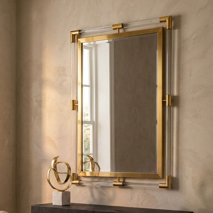 Gold-framed mirror on a beige wall with a decorative sculpture below.