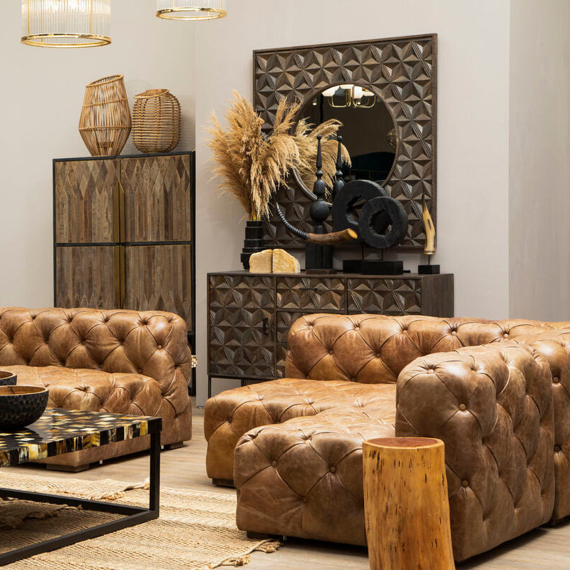 Modern living room with brown leather sofas, a coffee table, and decorative items.