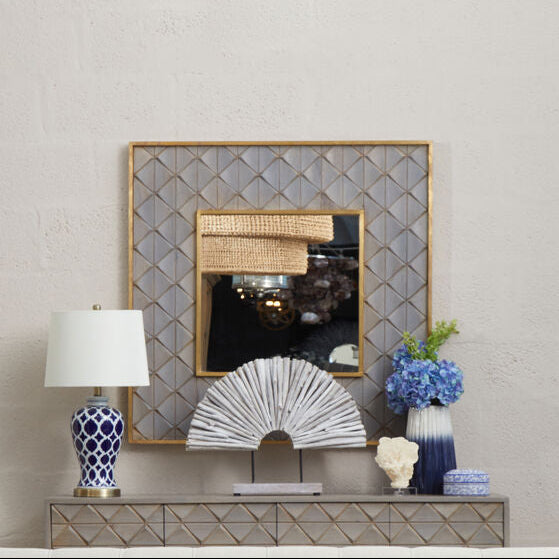 Living room with a gray tufted sofa, decorative mirror, and coffee table.