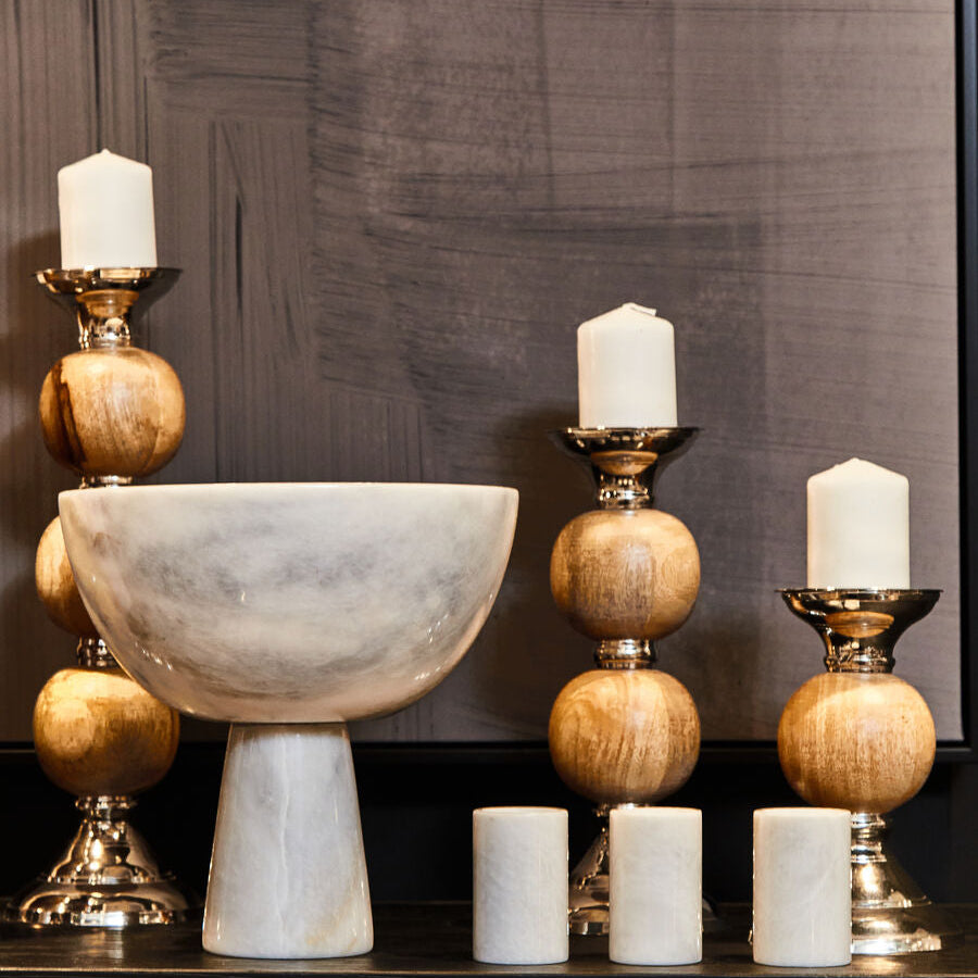 Decorative items including a marble bowl, candles, and wooden candle holders on a dark surface.