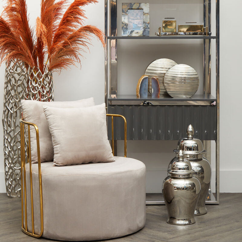 Modern interior with a beige armchair, decorative vases, and a glass cabinet.