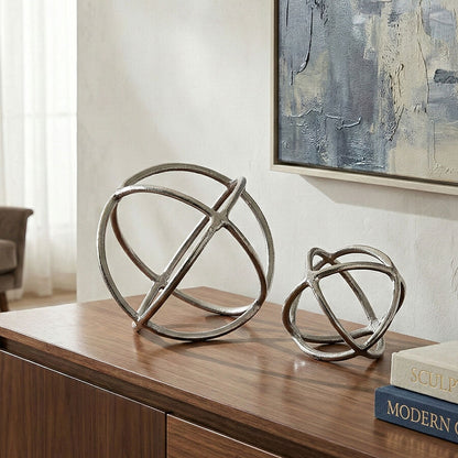 Decorative metal spheres on a wooden surface with abstract art in the background