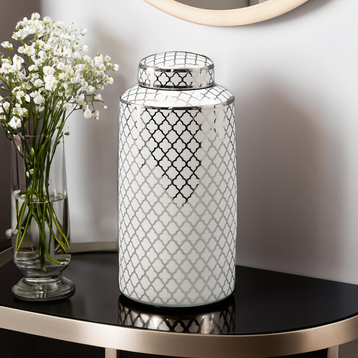 Decorative vase with geometric pattern on a table next to a small vase with white flowers.