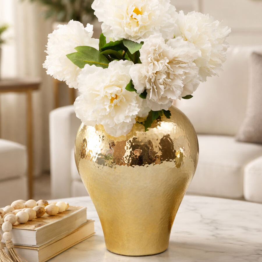 Gold vase with white flowers on a marble surface in a living room setting