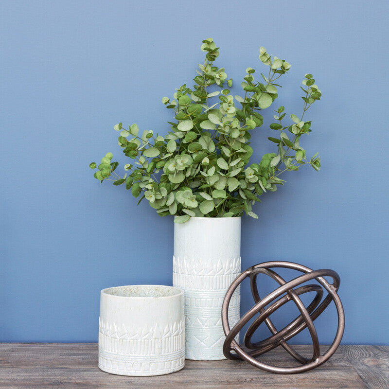 Vase with greenery on a wooden table against a blue wall