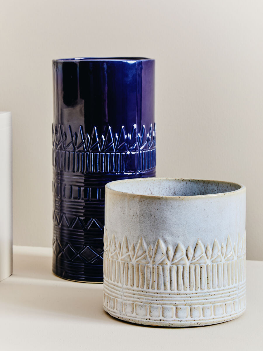 Two ceramic vases, one blue and one beige, on a light background