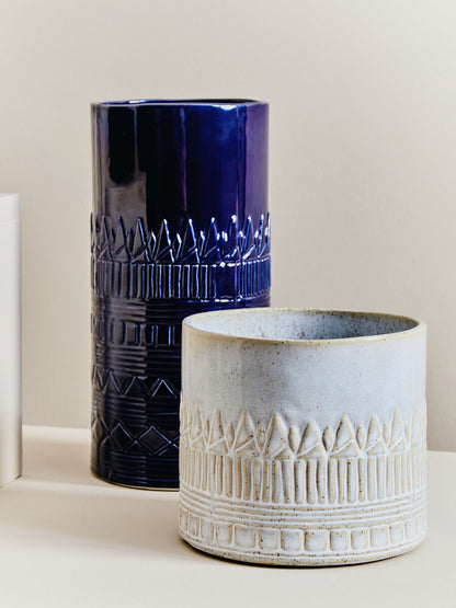 Two ceramic vases, one blue and one beige, on a light background