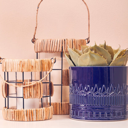 Blue textured planter with a succulent and wooden lanterns on a light background