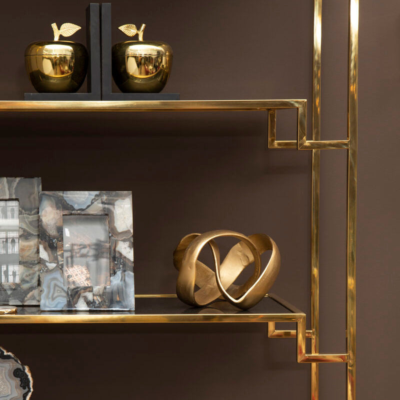 Gold-framed shelf with decorative items against a dark background