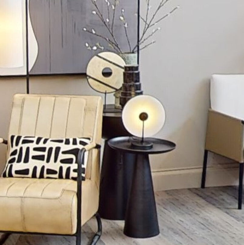 Modern living room with beige armchair, side table, and abstract wall art.