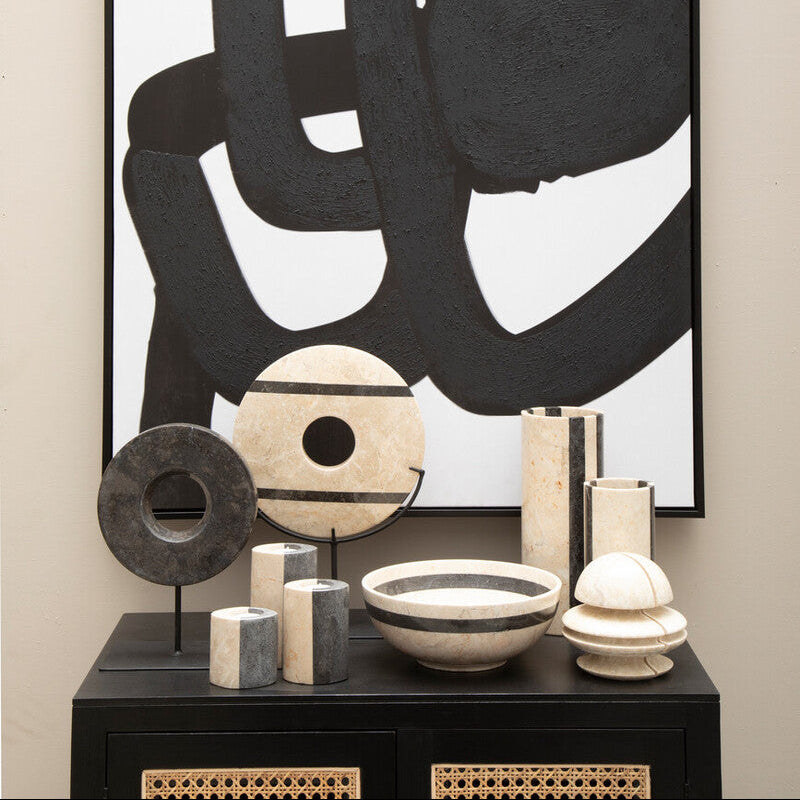 Abstract black and white artwork on a wall with decorative items below.