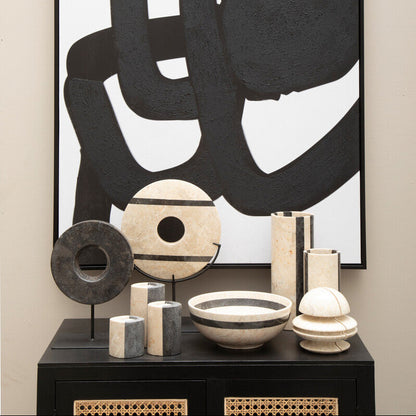 Abstract black and white artwork on a wall with decorative items below.