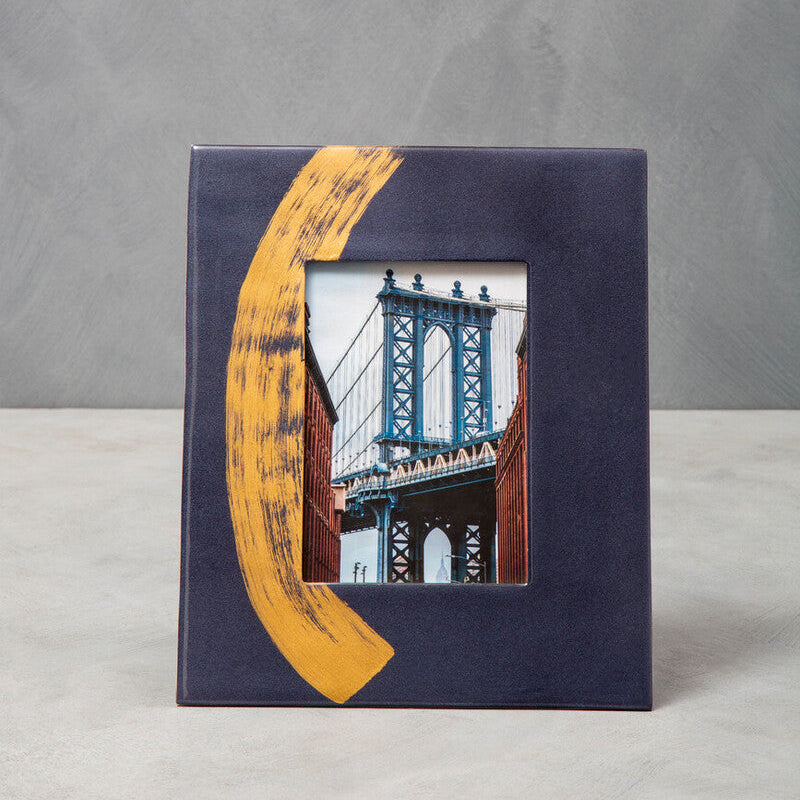 Framed artwork with a yellow ribbon and a small inset of a bridge on a gray background