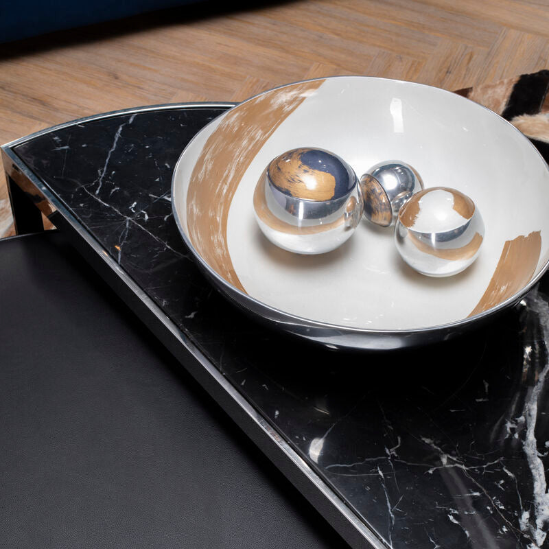 Decorative bowl with spherical objects on a black marble surface
