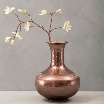 Copper vase with floral branch on a gray background