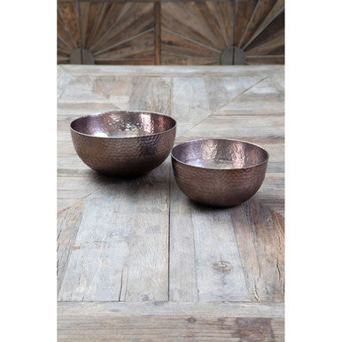 Two copper bowls on a wooden surface with a rustic background