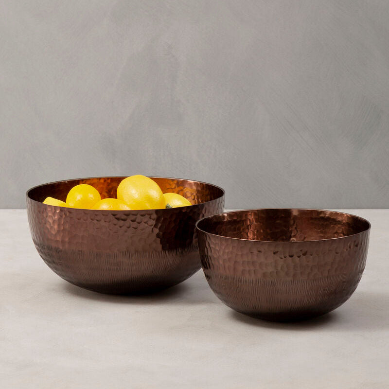 Two bronze bowls with lemons on a gray background