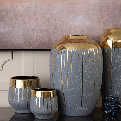 Set of decorative vases with gold accents on a shelf against a neutral wall.