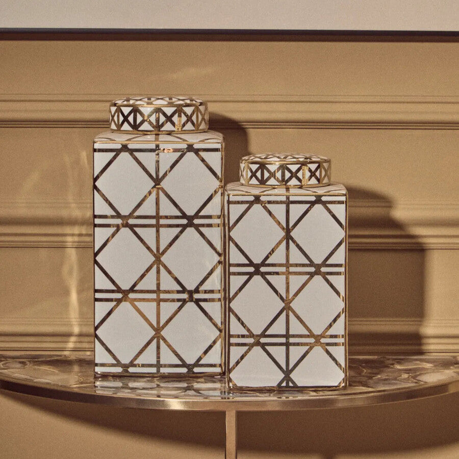 Two decorative vases with geometric patterns on a table against a beige wall.