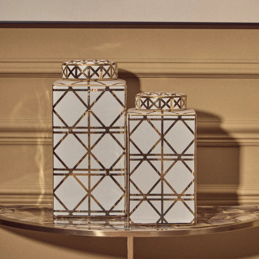 Two decorative vases with geometric patterns on a table against a beige wall.