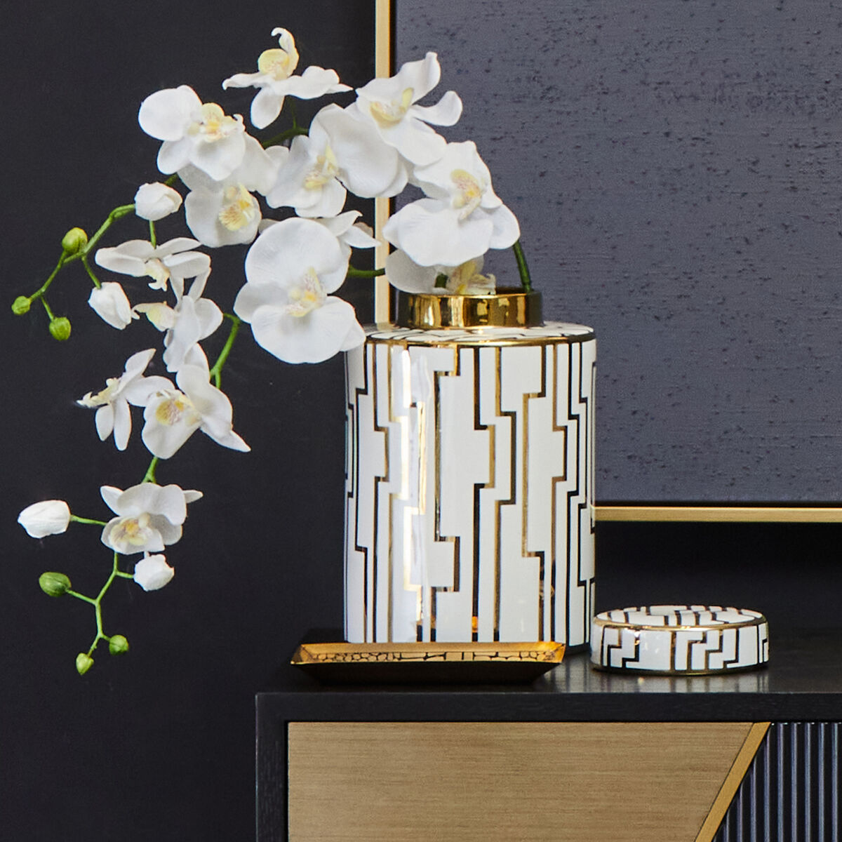 Decorative vase with geometric pattern and white flowers on a dark surface