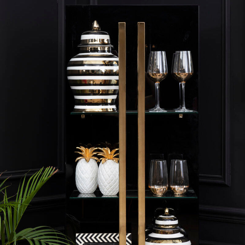 Black shelving unit with decorative items including vases and glasses against a dark wall.