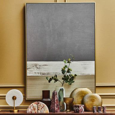 Decorative setting with a framed abstract painting on a wall, wooden cabinet with decorative items, and gold accents.