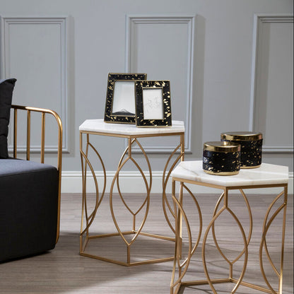 Modern black chair with gold frame and two marble tables with decorative items in a room.