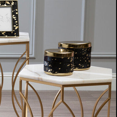 Modern black armchair with gold frame and marble tables in a room with gray paneled walls.