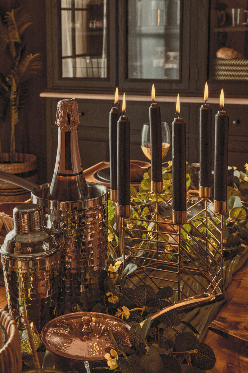 Decorative setup with bottles, candles, and a metal cart on a wooden table.