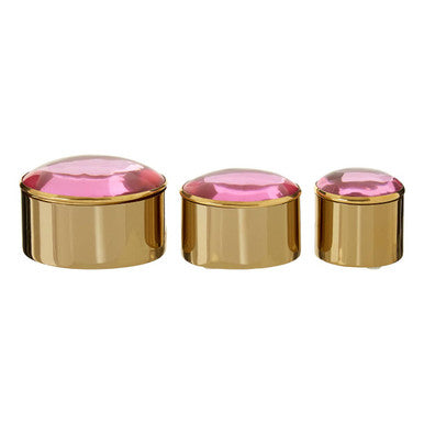 Three gold containers with pink lids on a white background