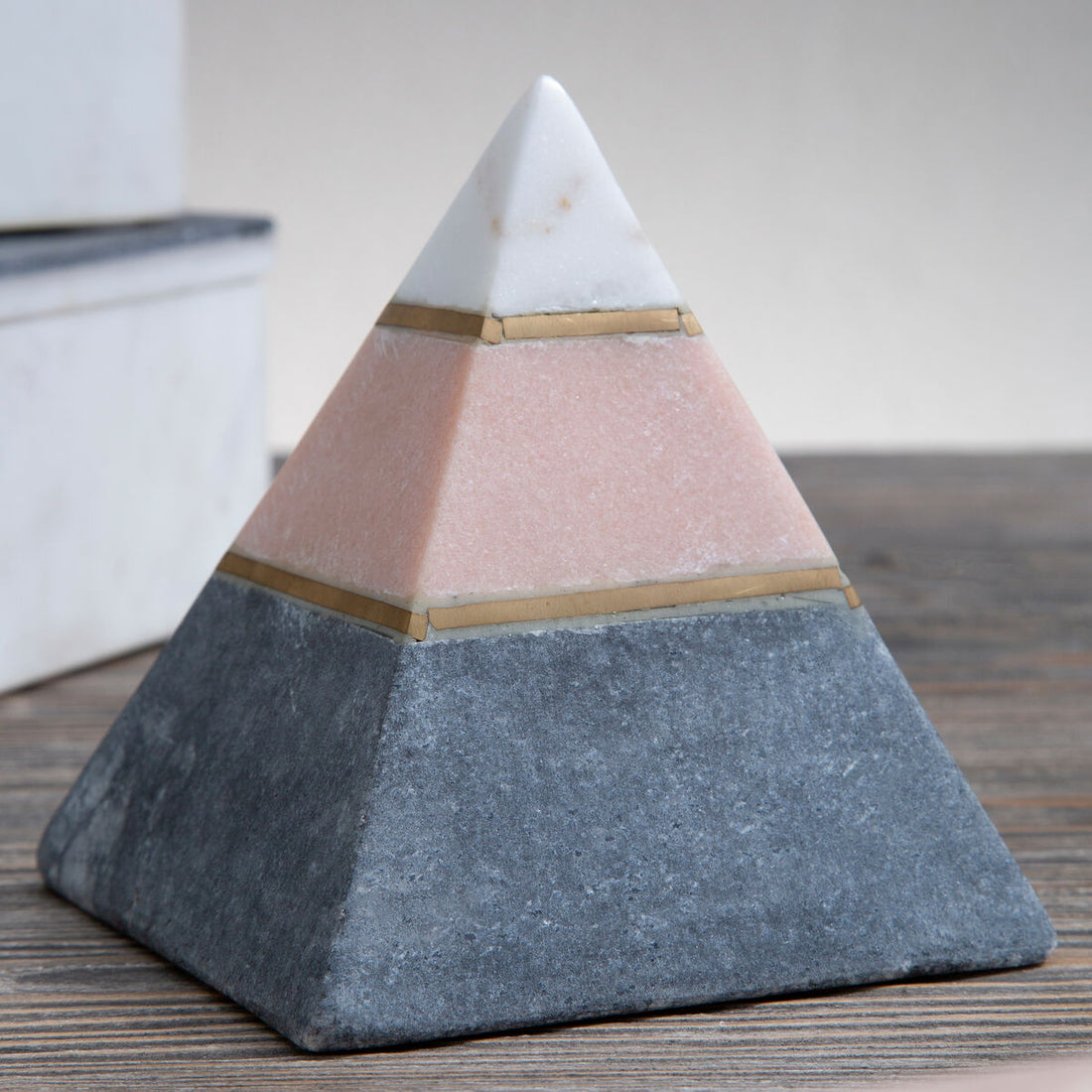 Pyramid-shaped object with three different colored layers on a wooden surface.