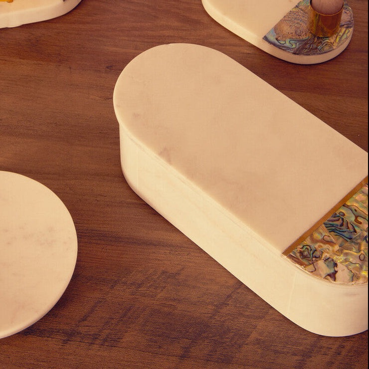 Decorative items including a cylindrical box, coasters with artistic designs, and a small cup on a wooden surface.