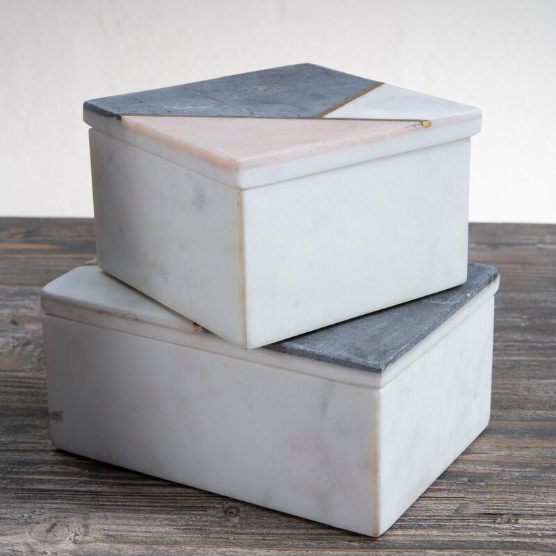 Two marble storage boxes stacked on a wooden surface with a neutral background