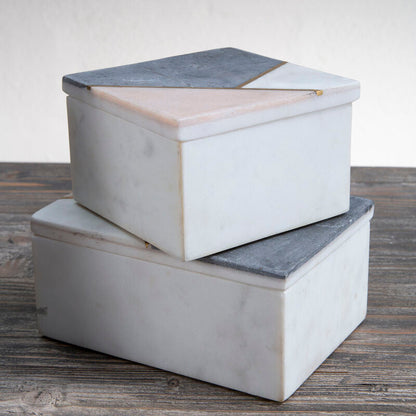 Two marble storage boxes stacked on a wooden surface with a neutral background