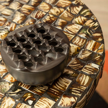 Black textured object on a mosaic-patterned table