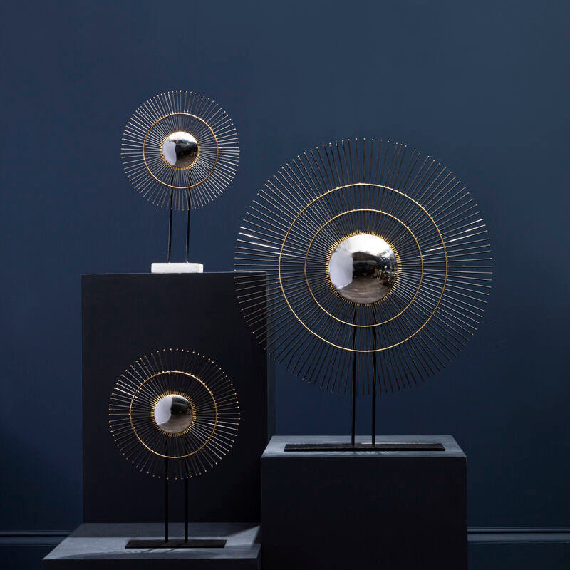 Decorative wall art pieces on black stands against a dark blue wall.