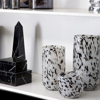 Decorative vases and sculptures on a white shelf against a white wall