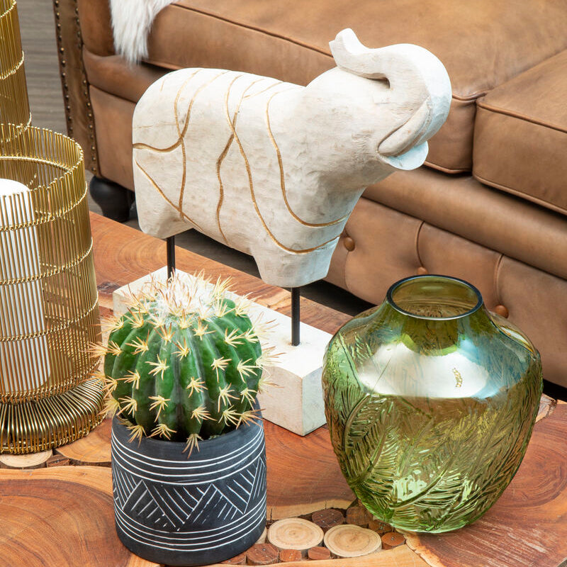 Decorative items on a wooden coffee table including a cactus, vase, and sculpture.