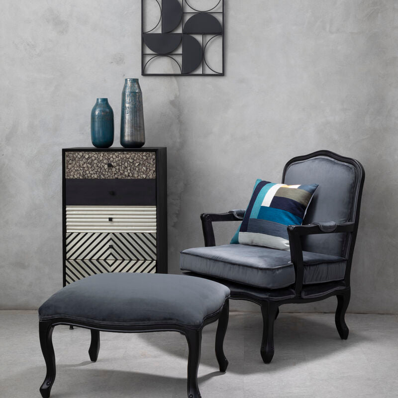 Gray armchair with ottoman and decorative items against a gray wall.