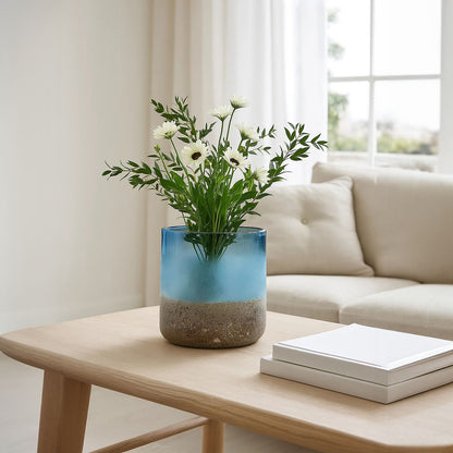 Glass vase with flowers on a wooden table in a living room setting