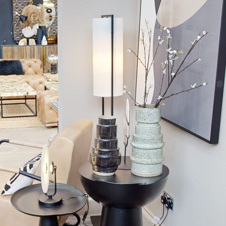 Modern interior with black side tables, lamp, and decorative elements.