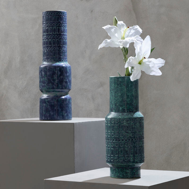 Two textured vases, one with flowers, on a neutral background