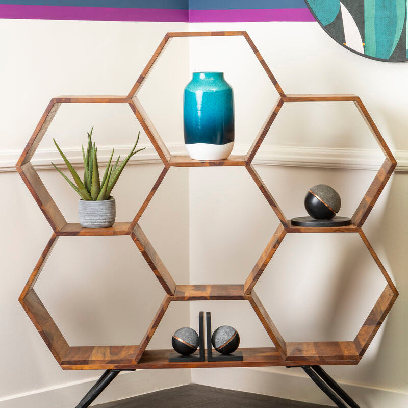 Hexagonal wooden shelf with decorative items against a white wall