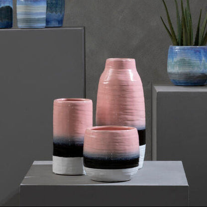 Vases with gradient colors on gray pedestals against a dark gray background